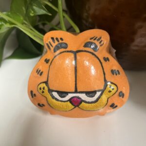 Orange cartoon cat figurine near plant.