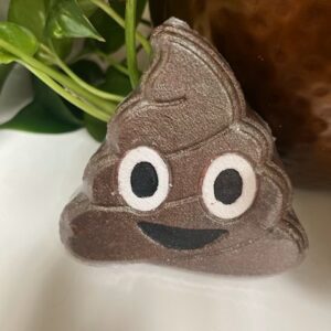 Smiling poop emoji-shaped soap near plant.